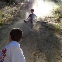 kids sliding down dirt slide